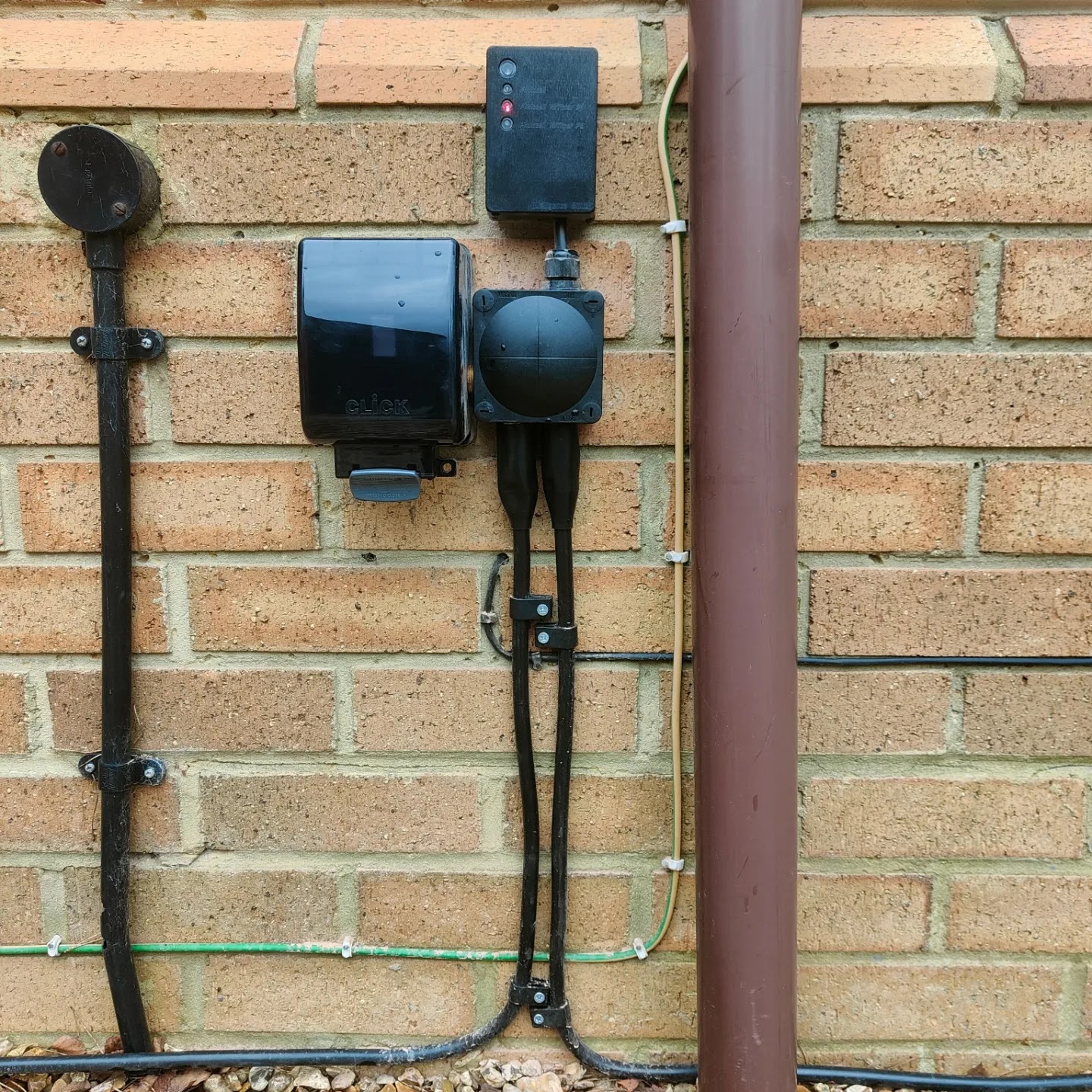 External power and junction boxes clipped neatly to brickwork for a garden supply.