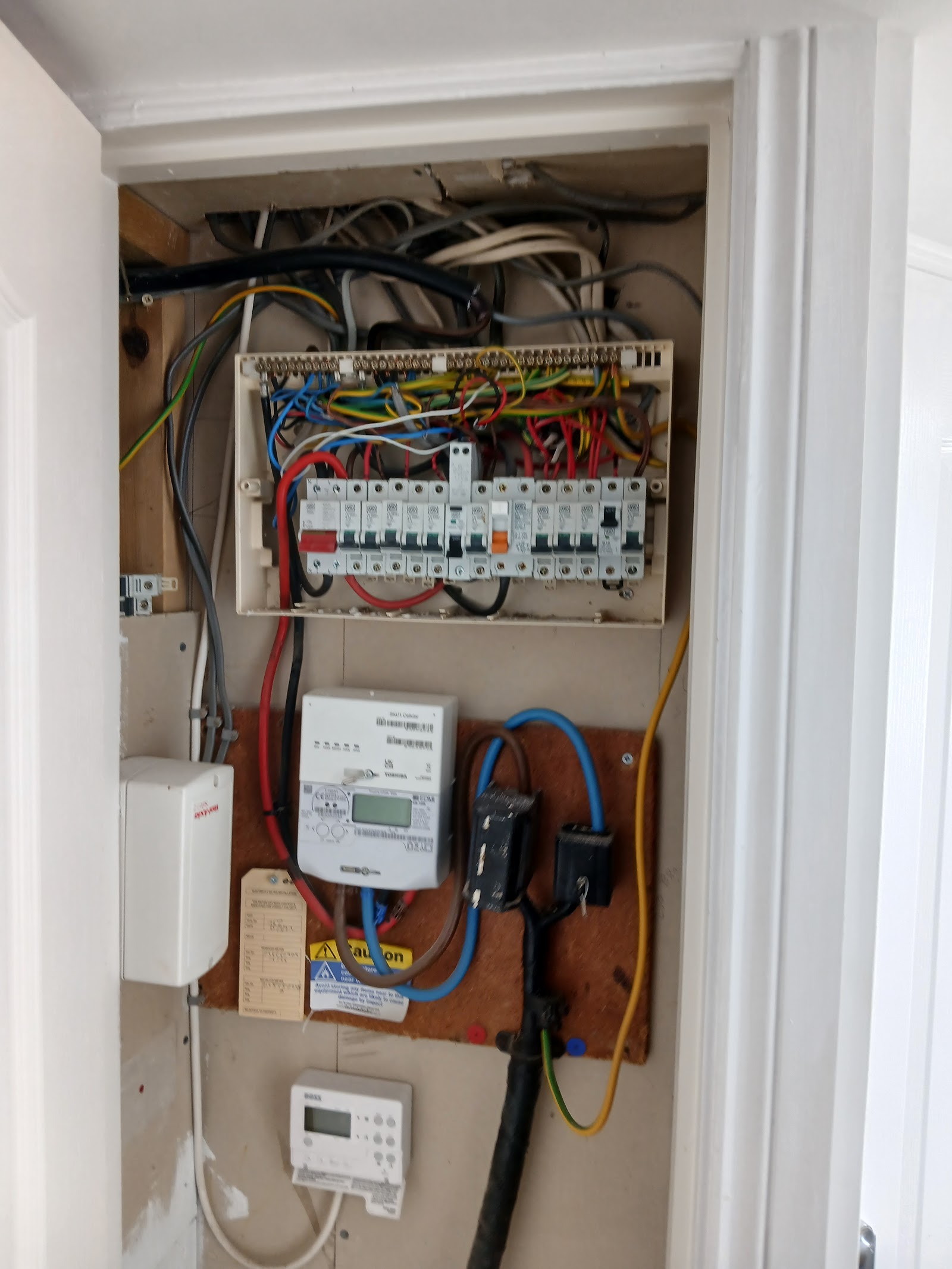 An older fuse board, meter and tangled tails — the kind of installation Andy replaces on a rewire.